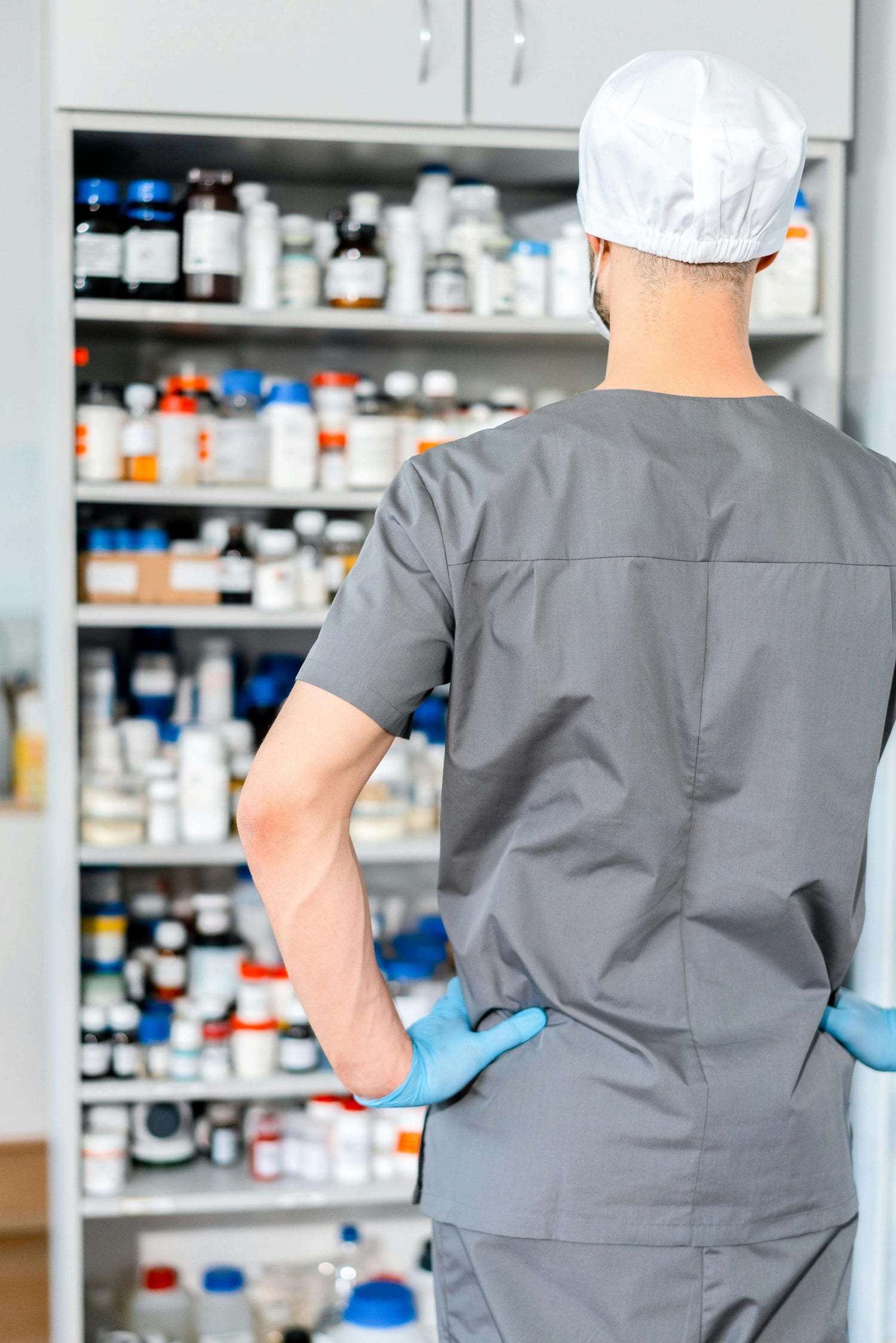 Medical professional in scrubs in front of supply cabinet – well-stocked aesthetic clinic